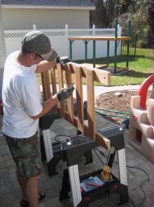 Mark splinter-proofing the swingset. Please take notice of the 2 new saw horses we had to buy for this project and compliment Mark on them because he's very proud of them. We went to 3 different home stores to find them. They're very special.